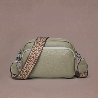 Sage green crossbody bag with wide woven strap and front zip pocket