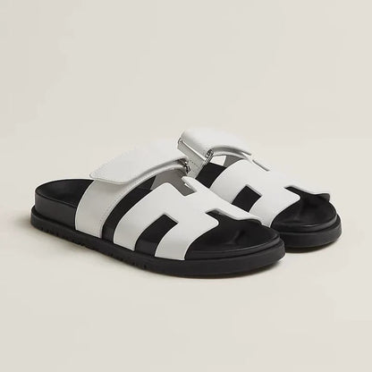 White flat slide sandals with black sole and adjustable strap